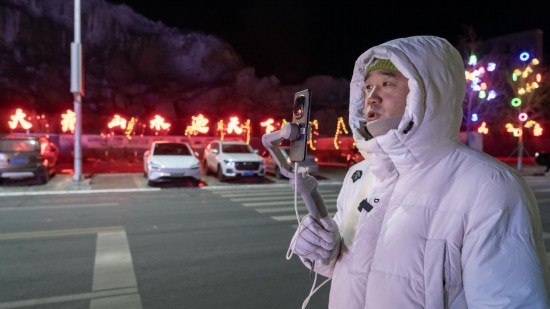 在吉林市阿什哈達霧凇觀景帶，霧凇播報員正在直播。新華社記者 李典 攝