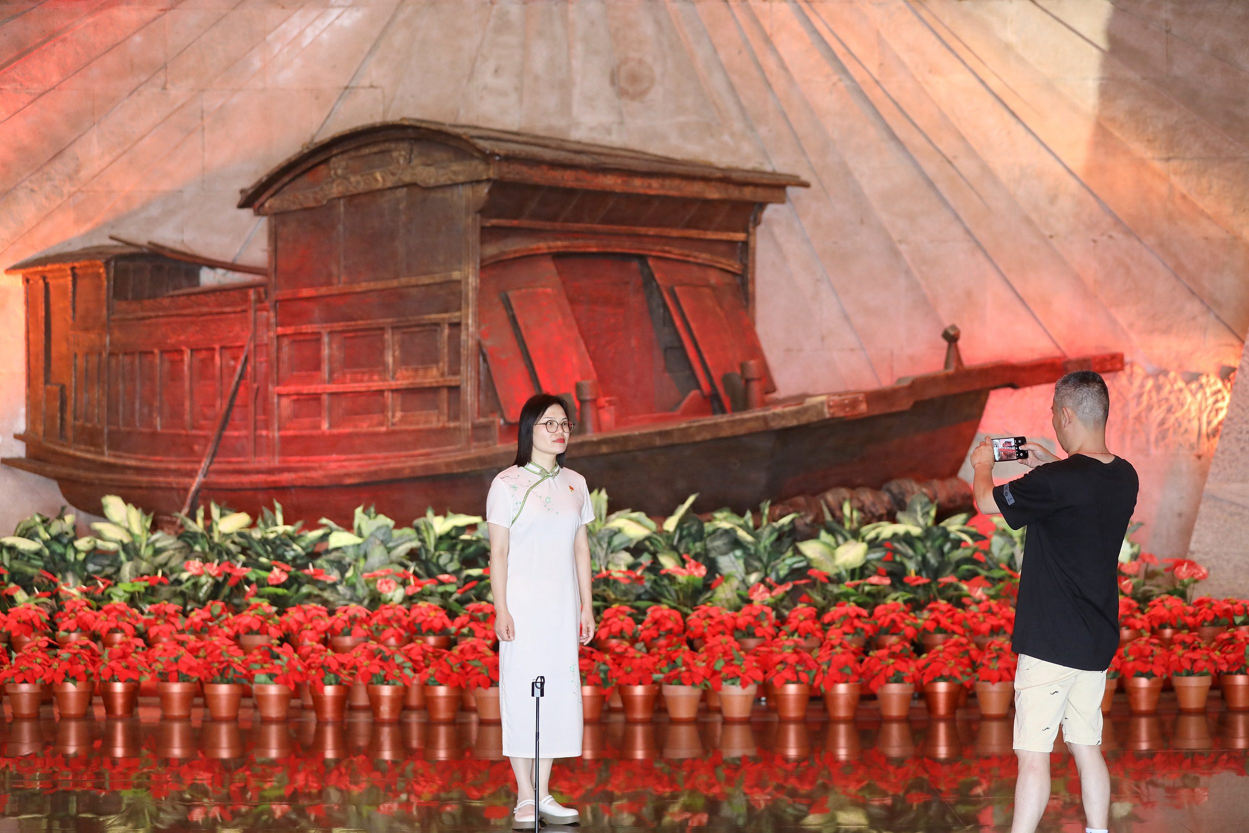 2025年6月24日，浙江嘉興，游客在南湖革命紀(jì)念館與紅船雕塑合影。（圖片來(lái)源：視覺(jué)中國(guó)）