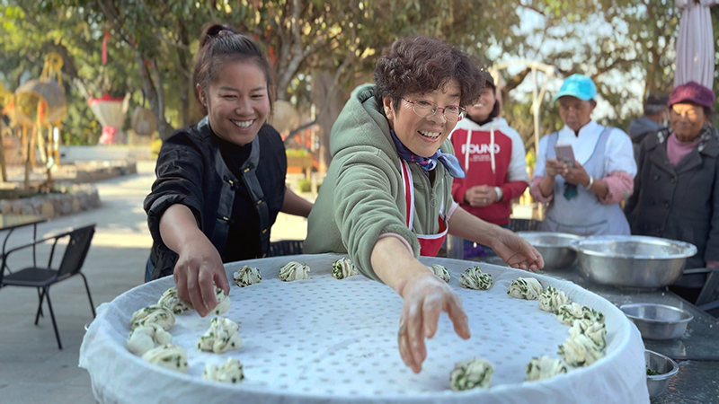 【2】旅居者趙發(fā)英（圖左二）教曼海村村民做花卷。陶思源-攝