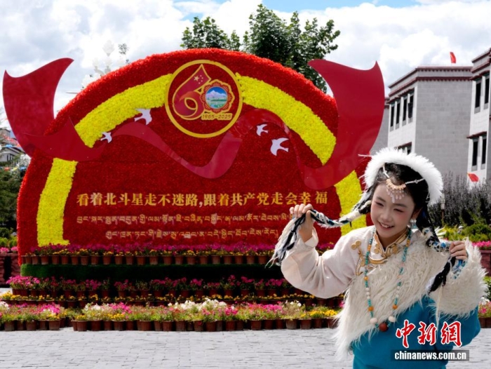 8月19日，隨著西藏自治區(qū)成立60周年慶?；顒优R近，拉薩氛圍濃。拉薩街頭，處處是張燈結彩的盛景，洋溢著一派祥和與歡騰的氛圍。圖為游客在拉薩大昭寺廣場上的大慶宣傳標語前留念。<a target='_blank' href='/'>中新社</a>記者 李林 攝